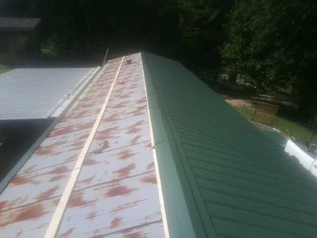 Old rusted panels beside newly installed green metal roofing — Wind Damage Roof Repair by Roofing Brothers in Mountville