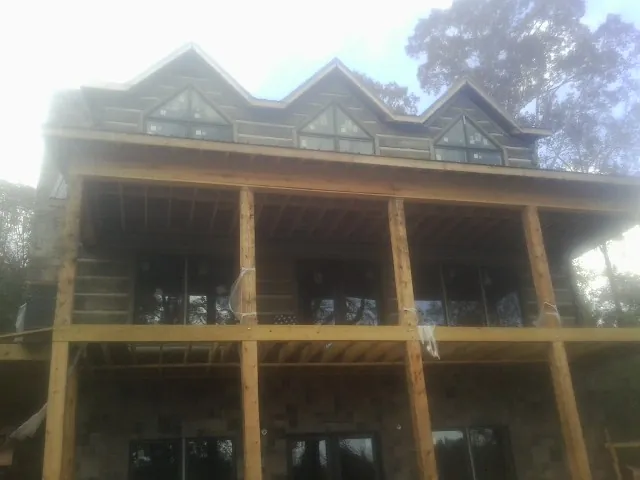 Dormers and porch framing on a large log home under construction — Roof Coating work by our crew in Mountville