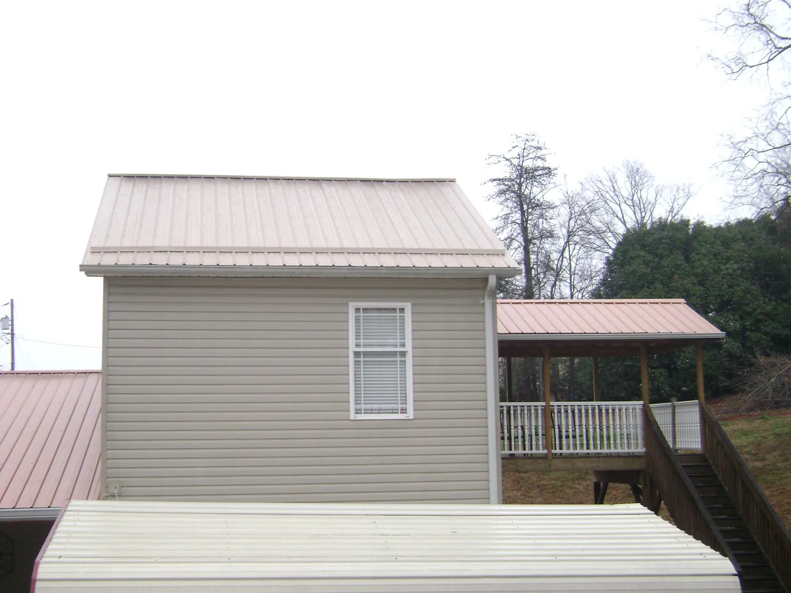 Tan metal roofs on a two story addition and attached porch, from a Roof Replacement job in Mountville